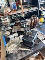 Overall view of vintage kitchen items including coffee grinders, graters, sifter, sugar bowl, aluminum baking molds and salt and pepper shakers.