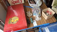 Photo of red metal Erector set box, bagged toy cars, and other toy components on wooden surface.