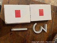 Two white house numbers 3 and 1 placed near their boxes with Design Within Reach logo