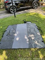 Dog car seat cover spread out on grass, showing full size and shape with visible attachment straps.