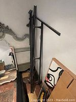 Photo showing the metal double bed frame leaning against the wall alongside decorative framed artwork.