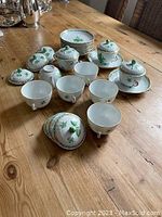 Overview of nine soup cups (some uncovered), ten plates stacked and one extra lid on tabletop