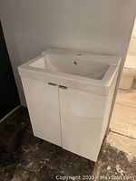 Front view of the white Ikea vanity cabinet with integrated sink, closed doors, showing overall configuration and condition.