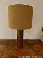Front view of modern table lamp with wood base and beige fabric shade