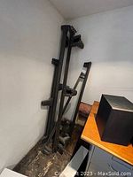 Black metal queen size bed frame parts leaning against a wall in corner.