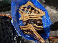 Blue bag filled with various wooden hangers, showing light to medium toned wood with metal hooks.
