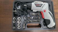 Electric screwdriver in case with charger cable and multiple screwdriver bits and socket attachments