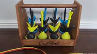 Lawn darts set stored in wooden EastPoint branded carrying case, showing darts upright with blue, yellow, and black fins and weighted bases.