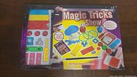 Full view of Magic Tricks Show box and accessories inside. Includes colorful magic props and booklet.