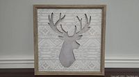 Front view of a 15 by 15 inch framed moose silhouette wall art with patterned background