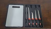 Full set showing white cutting board, sharpening steel, and five knives