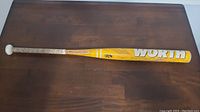 Full side view of the yellow WORTH baseball bat showing the logo and handle tape.