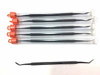 Five new black metal dual-ended cleaning pick tools in clear plastic tubes with orange caps, laid out flat and one tube open showing the tool