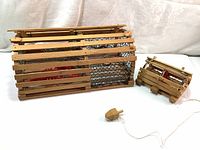 Large and small handmade wooden lobster traps with netting and cork floats shown side by side on a cloth background.
