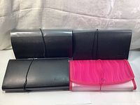 Four receipt and document organizers with elastic band closures, three black and one pink, showing exterior view.