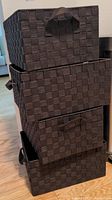 Stack of three dark brown faux woven storage baskets with handles shown upright.