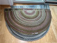 Stacked view of multi-colored and sea glass braided half-circle rugs showing texture, pattern, and LL Bean brand label.