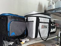 Three soft side insulated coolers on a shelf, showing varying sizes and colors with logos including Marine and Titan.