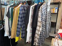Photo showing a rack with various men's tall XL shirts and coats including plaid long sleeves, solid colors, and short sleeves on hangers