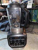 Front view of Ninja HB152 blender showing jar, handle, and control panel with various preset buttons and digital screen.