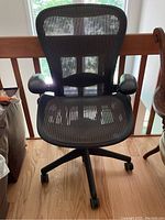 Front view showing mesh back and seat, armrests and wheel base