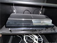 Top angled view of PlayStation 3 console showing front disc drive slot and glossy surface.