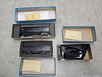 Three HO scale model railroad items: a powered locomotive, crane car, and additional car in original blue boxes with foam inserts and paperwork.