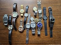 Top view of all watches laid out on wood surface showing different brands, band types, faces, and colors.