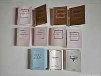 11 full perfume tester samples arranged on white background showing folded sample cards with spray vials visible