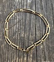 Gold-tone vintage necklace laid flat on wood background, showing chain design and length.
