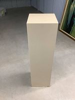 Front view of white rectangular display pedestal showing overall shape and condition.