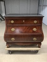 Front view of the Louis style 3 drawer bombe commode showing the wood finish, brass pulls, and curved drawer fronts.