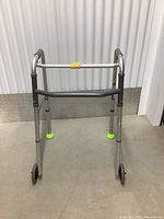 Front view of the foldable medical assist walker showing padded hand grips and two wheels.