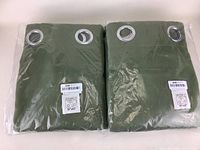 Two green curtain panels folded and vacuum-sealed in original packaging showing metal grommets and size label 52x63 inches