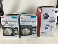 Three boxes comprising the lot: two boxes of 3M 8210V N95 particulate respirator masks (each containing 10 masks) and one box of Honeywell N1105 XL SAF-T-FIT PLUS masks (containing 20 masks) on a white surface.