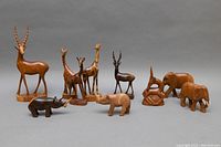 Overview of all ten hand carved wooden animal sculptures showing antelope, giraffes, rhinos and elephants