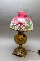 Full view of the antique table lamp with hand-painted floral glass shade, brass base, and clear chimney.