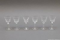 Set of six clear cut crystal liquor glasses with intricate bowl design and starburst bases.