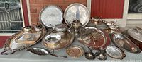 Front view of all pieces displayed on table showing variety of trays, pots, dishes and candle holders