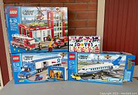 Four LEGO boxes displayed showing Fire Station, Toys R Us Truck, Passenger Plane and DOTS sets
