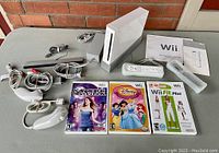 Overall view of Wii console, accessories, remotes, nunchuks, and game cases on table