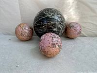 Four loose world globes, three small pinkish colored globes and one large black globe.