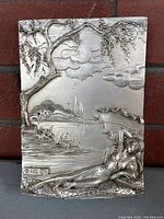 Front view of silver repousse plaque showing detailed embossed scene with reclining woman under tree, signed ARG 925.