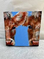 Front view of the square canvas painting showing two cow faces with detailed brown and white fur on blue background.