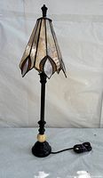 Full view of the vintage stained glass table lamp showing the shade, black base, cream accent sphere, and power cord.