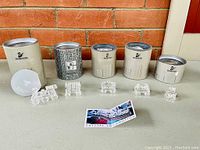 Full shot of all five Swarovski crystal locomotive train pieces arranged in front of their original cylindrical boxes. Also includes the authenticity certificate and promotional card.