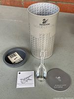 Clear crystal violin figurine with detailed faceted body, neck, and tuning pegs, accompanied by original tube and paperwork including certificate and leaflet.
