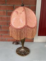 Full view of vintage table lamp including metal base and peach silk shade with fringe, showing overall condition and design.