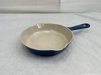 Photo showing the interior and side view of the skillet with cream-colored enamel inside and cobalt blue exterior with double spouts.
