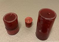 Three red wild berries scented candles of varying sizes: 6", 4", and 2" tall, placed on a neutral surface.